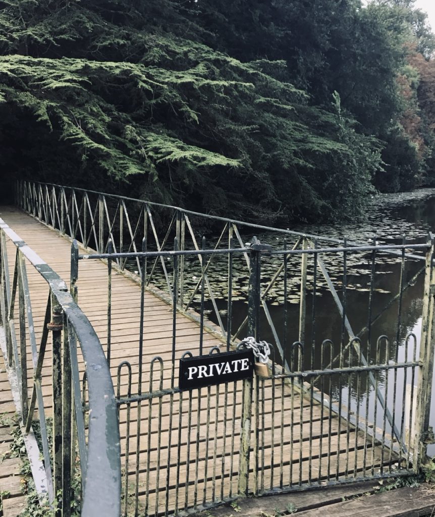 footbridge over water with gate that says private